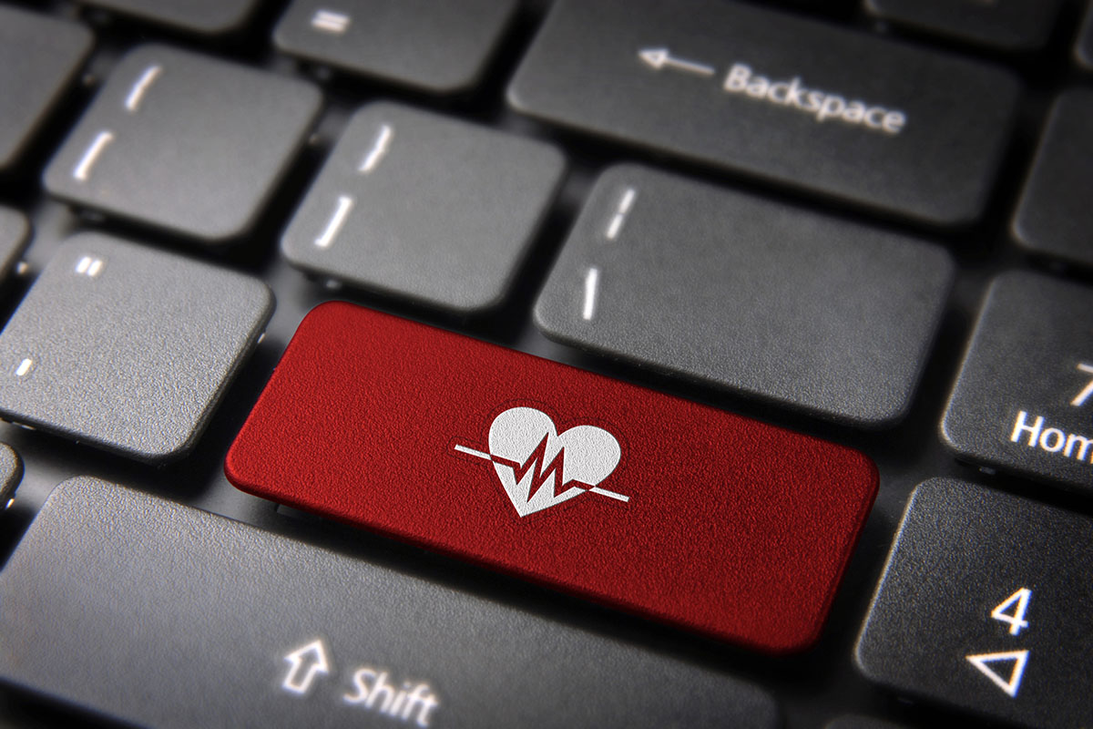 A close-up of a computer keyboard, highlighting a red key featuring a heart and EKG line graphic.
