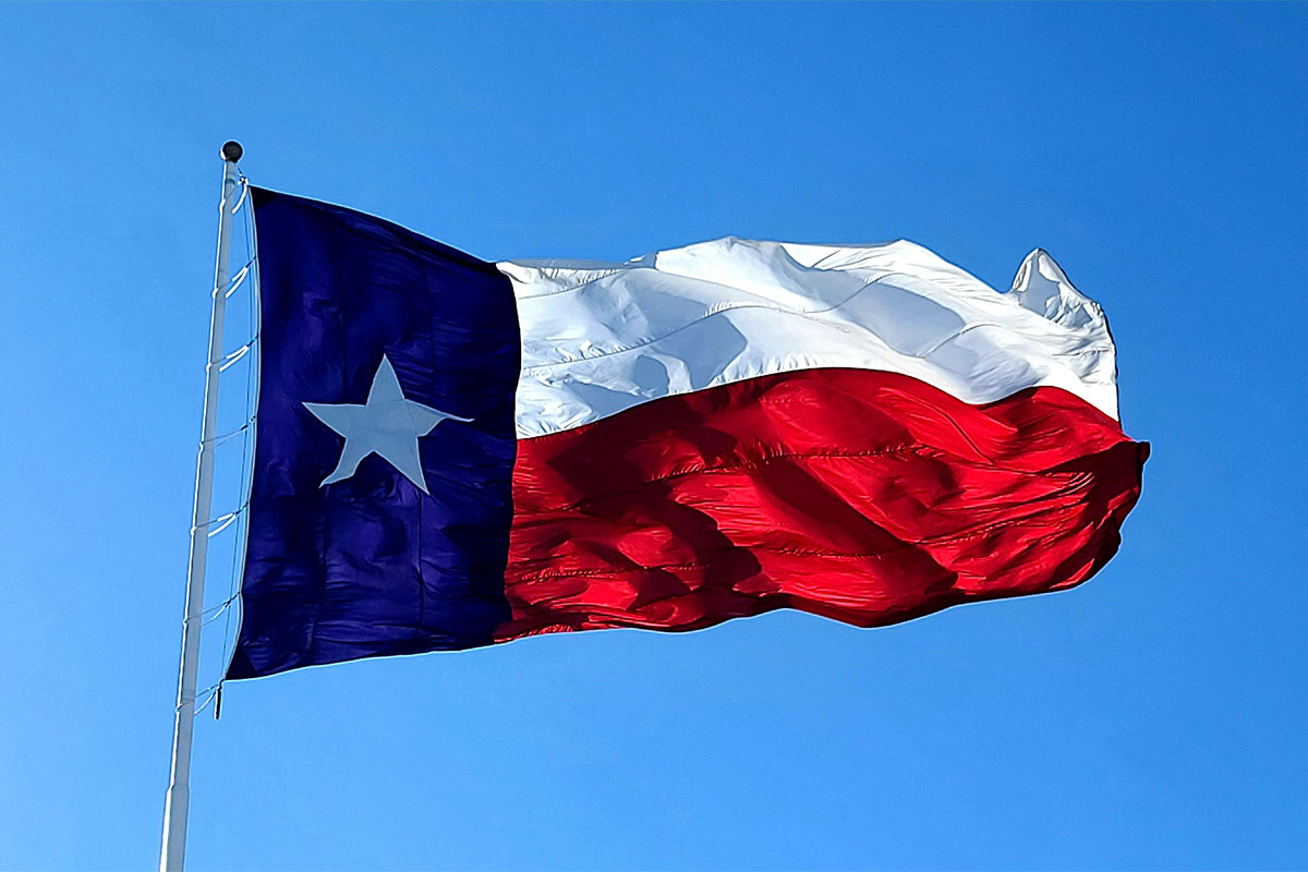 The Texas flag waving against a clear blue sky.