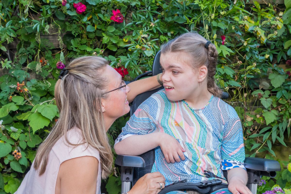 A child in a wheelchair talking with a family caregiver.