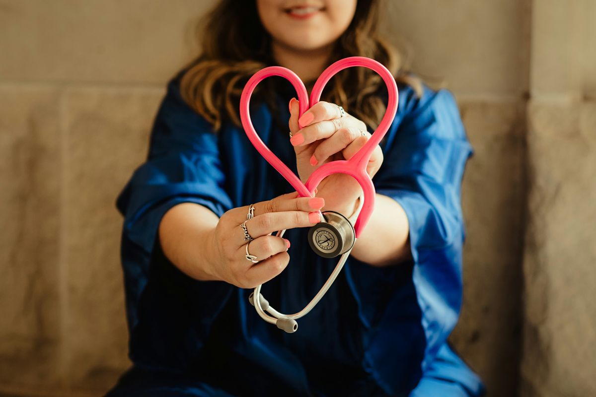 A healthcare provider holding a stethoscope in the shape of a heart.